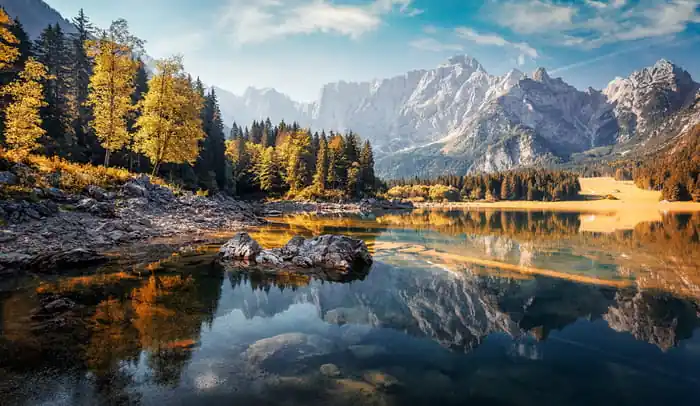 Fototapeta Awesome Sunny Landscape In The Forest. Wonderful Autumn Scenery. Picturesque View Of Nature Wild Lake. Sun Rays Through Colorful Trees. Incredible View On Fusine Lakeside. Amazing Natural Background Nowość
