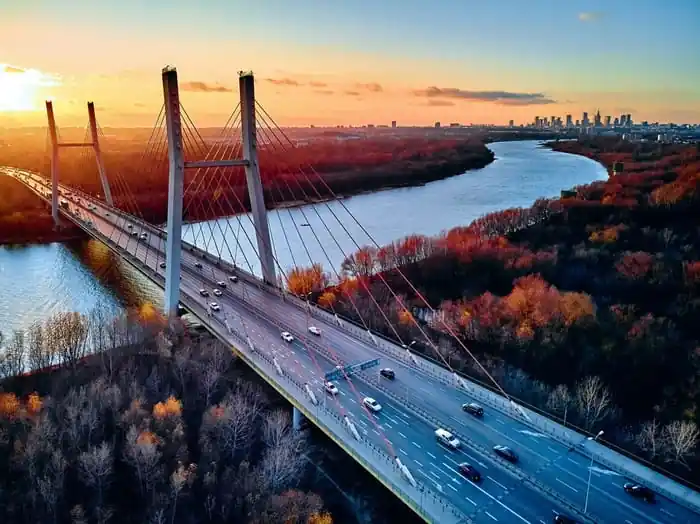 Fototapeta Beautiful Panoramic Aerial Drone View To Cable-Stayed Siekierkowski Bridge Over The Vistula River And Warsaw City Skyscrapers, Poland In Gold Red Autumn Colors In November Evening At Sunset Zniżka