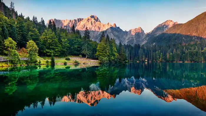 Fototapeta Calm Morning View Of Fusine Lake. Colorful Summer Sunrise In Julian Alps With Mangart Peak On Background, Province Of Udine, Italy, Europe. Beauty Of Nature Concept Background. Zniżka